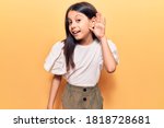 Small photo of Beautiful child girl wearing casual clothes smiling with hand over ear listening and hearing to rumor or gossip. deafness concept.