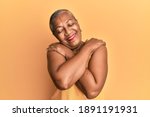 Senior african american woman wearing casual style with sleeveless shirt hugging oneself happy and positive, smiling confident. self love and self care 