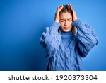 Small photo of Young beautiful blonde woman wearing winter wool sweater over blue isolated background suffering from headache desperate and stressed because pain and migraine. Hands on head.