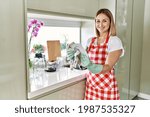 Young caucasian girl smiling happy wipping dish at the kitchen.