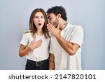 Small photo of Young couple wearing casual clothes standing together hand on mouth telling secret rumor, whispering malicious talk conversation