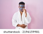 Young hispanic man wearing beauty face mask and bath robe mouth and lips shut as zip with fingers. secret and silent, taboo talking 