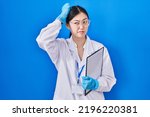 Chinese young woman working at scientist laboratory confuse and wondering about question. uncertain with doubt, thinking with hand on head. pensive concept. 
