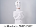Blonde caucasian woman wearing bathrobe standing backwards looking away with crossed arms 