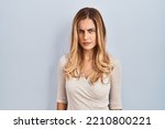 Young blonde woman standing over isolated background skeptic and nervous, frowning upset because of problem. negative person. 