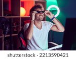 Small photo of Young hispanic man streamer smiling confidetn wearing thug life glasses at music studio