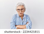 Small photo of Senior woman with grey hair standing over white background skeptic and nervous, disapproving expression on face with crossed arms. negative person.