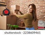 Small photo of Young latin woman smiling confident holding packages at hew home
