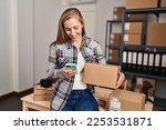 Young blonde woman ecommerce business worker using smartphone holding package at office
