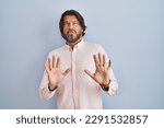 Small photo of Handsome middle age man wearing elegant shirt background moving away hands palms showing refusal and denial with afraid and disgusting expression. stop and forbidden.