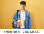Small photo of Hispanic teenager wearing student backpack and holding books with a happy and cool smile on face. lucky person.