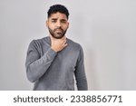 Small photo of Hispanic man with beard standing over white background touching painful neck, sore throat for flu, clod and infection