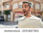 Young hispanic man standing with surprise expression at street