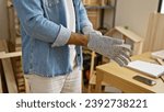 Small photo of Crafty hands of a hispanic man, a glove-wearing carpenter immersed in woodwork at a professional carpentry workshop