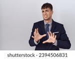 Small photo of Young hispanic business man wearing suit and tie disgusted expression, displeased and fearful doing disgust face because aversion reaction. with hands raised