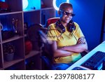 Small photo of African american woman streamer wearing thug life glasses sitting with arms crossed gesture at gaming room