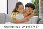 Small photo of Confident mother and daughter sharing a joyful hug, smiling heartily while sitting on the living room sofa at home aE“ a beautiful expression of family love and happiness
