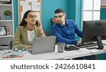 Small photo of Two canny coworkers, the tale of a cheating man and woman using a smartphone and computer in the office