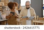 Small photo of Two expert carpenters in the throes of sanding a wood plank using touchpad, embracing technology in their traditional carpentry workshop