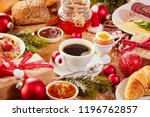 Christmas Intercontinental breakfast table with an assortment of tasty fresh food, coffee, gifts and colorful red decorations sprinkled with winter snow