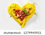 Decorative heart shaped pasta still life formed of cooked spaghetti topped with tomatoes, basil and parmesan cheese