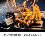 Small photo of Freshly lit barbecue fire with logs of burning wood over small chips of kindling in a portable BBQ