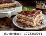 Close up on a portion of gourmet tiramisu Italian dessert topped with a sprig of mint served on a plate at table in a side view