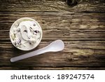 Tub of creamy Italian ice cream with a plastic disposable takeaway spoon served on an old weathered wooden table at a cafeteria for a refreshing summer treat, overhead view with copyspace