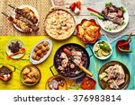 Top down view of various home made Brazilian recipes cooked and displayed on colorful textures and tablecloths