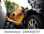 Pretty, young woman checking the state of a car for insurance purposes, prior to start driving it after renting it from a car rental. Automotive damage liability concept.
