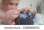 Small photo of Cute Creative Caucasian Girl Trying to Untangle Hank Skein of Yarn