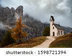 The small and beautiful church of cappella di san Maurizio at the Passo gardena pass in the Dolomites of the South Tyrol in Italy early in autumn with fog covering the dolomite mountains.