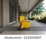 Small photo of plastic yellow mop bucket and wringer trolley set. cleaning supplies. with the words achtung in 'german' and 'cuidado' in spanish which means attention