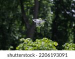 A quadcopter with a digital camera hovered above the bushes in the forest