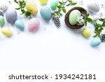 Colorful Easter eggs with spring blossom flowers over white  background. Colored Egg Holiday border. 