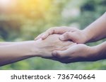 Two people holding hand together over blurred nature background,Business man and woman shaking hands,helping hand  and world peace concept with copy space