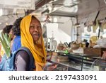 Small photo of Clack Muslim woman in hijab smiling outdoors on a market food. African Islamic lady buying food the street street stall with backpack with vegetables.