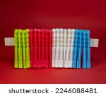 colored plastic pegs lined up next to each other. Close-up on red background.