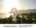 Small photo of Golden hour over the ferris wheel, treetops, lagoon and hilly backdrop of Cairns Esplanade - Coral Sea, Cairns; Far North Queensland, Australia