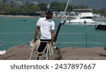 Small photo of Phuket, Thailand, 25, February, 2024: Sailor with a mooring line in his hands, a sailor moors a yacht at the pier
