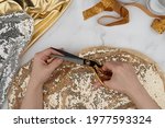 Female hands crafting clothes. Cut and sew customized garments. Gold scissors, threads, fabrics on a marble table. Sewing feminine, festive, glamorous, evening, wedding dresses, bridesmaids dress.