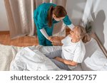 Small photo of Nurse helping an elderly woman at her home. Solicitous professional medical female staff caring in a geriatric institution with a senior patient. Lifestyle nursing service.