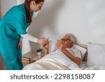 Nurse brought pills to elderly man at his home. Solicitous professional medical female staff caring in a geriatric institution with a senior patient. Lifestyle nursing service.