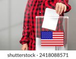 A voter casts a ballot into a ballot box on election day, USA flag.