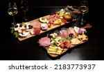Small photo of Wine and charcuterie and cheese board with a place for text. Prosciutto di Parma ham, blue cheese. Italian appetizers or antipasto set with gourmet food on table top view. Mixed delicatessen