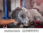 Auto mechanic working on car automatic transmission in auto repair shop.