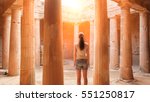 Small photo of Travel Cyprus - Back view of young woman standing between columns in ancient temple ruins on Cyprus. Tomb raider searching for a treasure