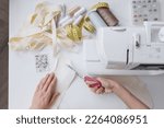 top view, woman on sewing machine creates clothes and suits, female cutter fashion designer couturier makes collection of dresses. home workshop or atelier of individual tailoring. handmade work area