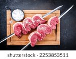Small photo of Raw dry aged wagyu picanha barbecue skewer from the cap of rump beef sliced and with salt offered as top view on a wooden rustic cutting board