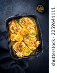 Small photo of Traditional Italian deep-fried chicken piccata with capper and lemon slices offered as top view in a rustic old roasting pan with copy space